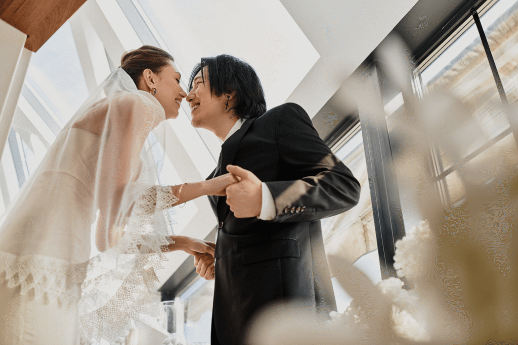 Is the Wedding Industry Dying in 2026? A Clear Look at What’s Changing 3 A bride and groom smile at each other, holding hands and leaning in for a kiss. Surrounded by natural light, their moment captures the magic that wedding professionals bring to life in today’s ever-evolving wedding industry.