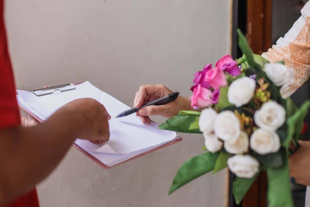 Is WeddingWire Worth It? A Guide for Wedding Venues 1 Two people signing off on a flower delivery for a wedding.