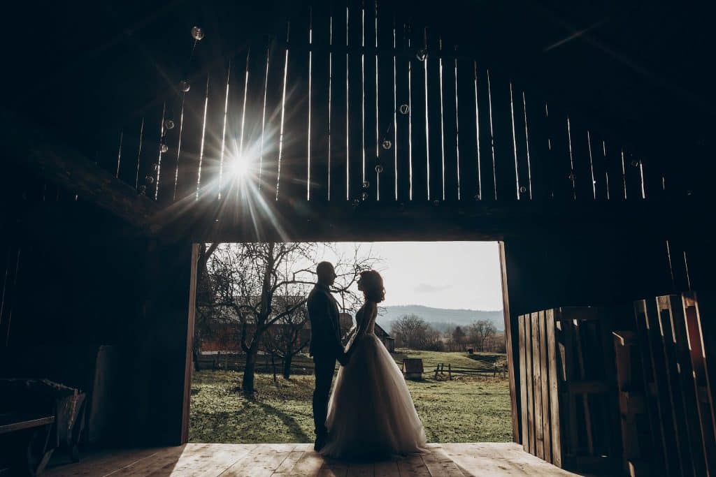 How Much Does Wedding Wire Cost for Wedding Venues? (And Is It Actually Worth It?) 4 Silhouetted couple inside a rustic barn venue with sunlight streaming through, a common venue style shown when evaluating how much does wedding wire cost