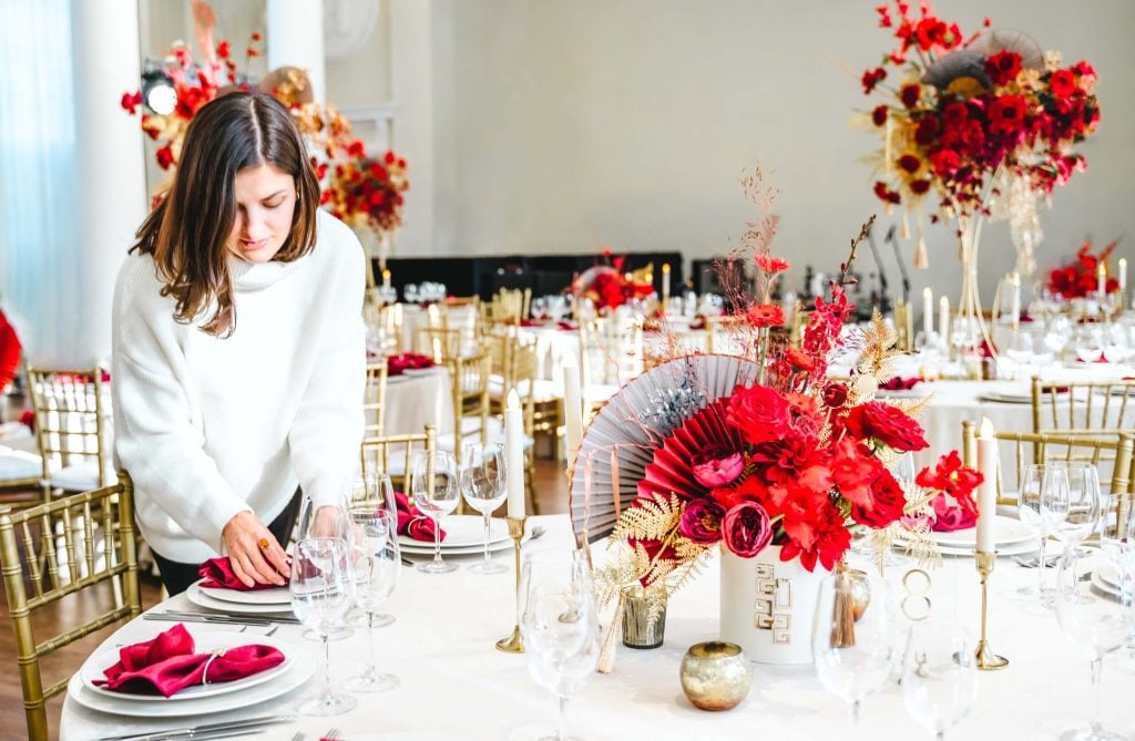 Wedding Venue Off Season Booking Strategy: Mid-Week + Shoulder-Season Plays 4 Venue team member arranging flowers inside a modern wedding space prepared for an off-season celebration.