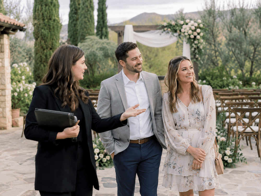 How to Improve Your Wedding Venue Tour Close Rate: 5 Tips + Practical Advice 2 Couple taking an outdoor wedding venue tour with a venue coordinator while viewing the ceremony space and discussing details that can affect the venue tour close rate.