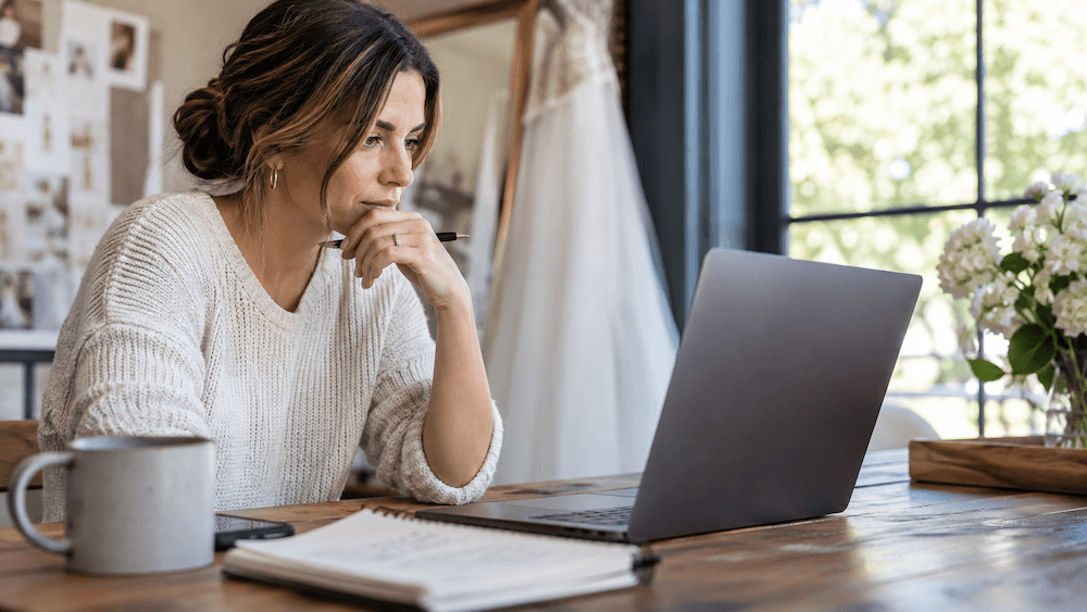 A wedding venue owner at a computer contemplating Are The Knot Leads Fake or Real?